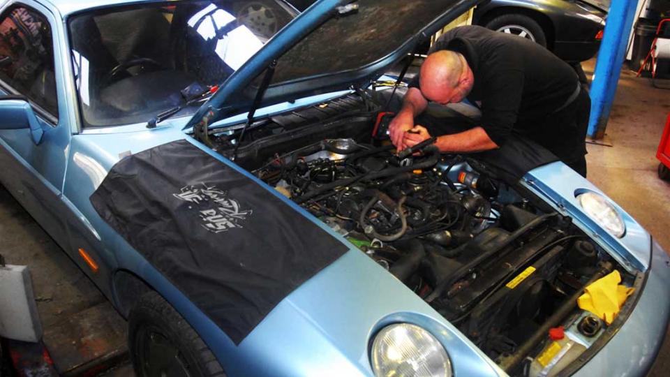 Ashley changes the spark plugs in a Porsche 928 S2