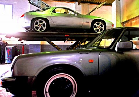 A silver Porsche 928 rides high in the Devon workshop for MOT test